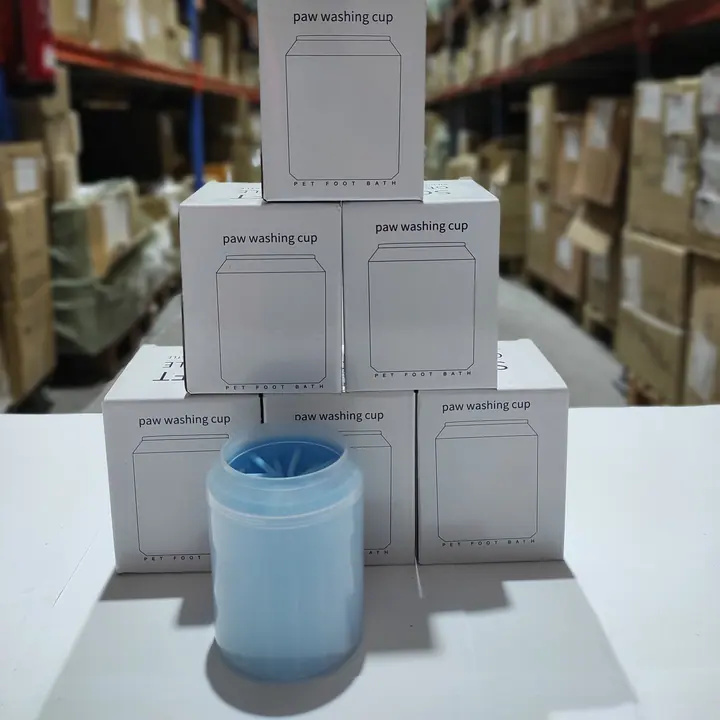 Vaso limpiapatas PawClean azul delante de una pila de cajas del producto en el almacén